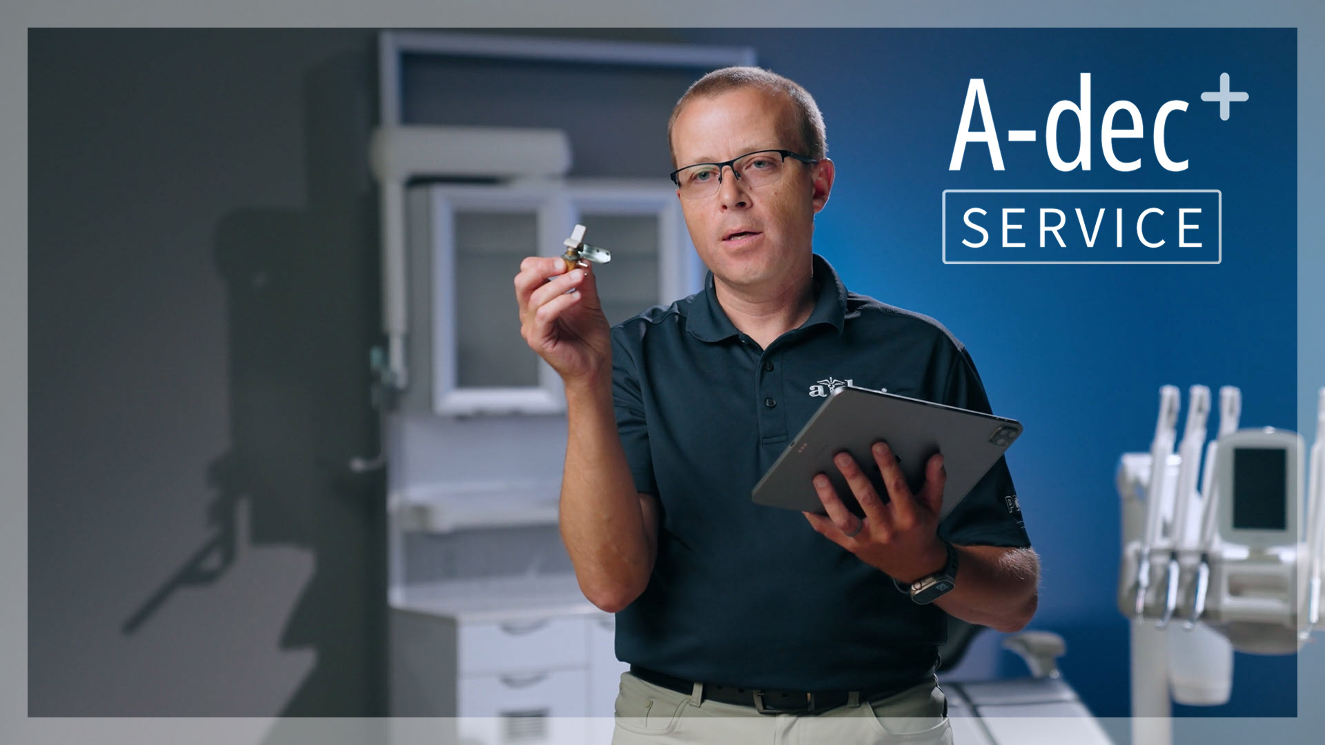 Man holds up a dental equipment part while demonstrating the A-dec+ Service app on an iPad