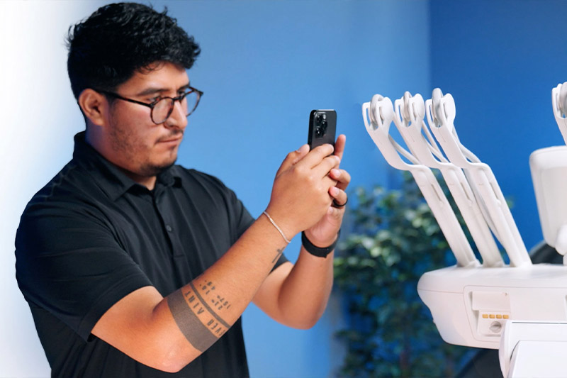 An A-dec authorized service person uses a phone to identify parts on an A-dec delivery system