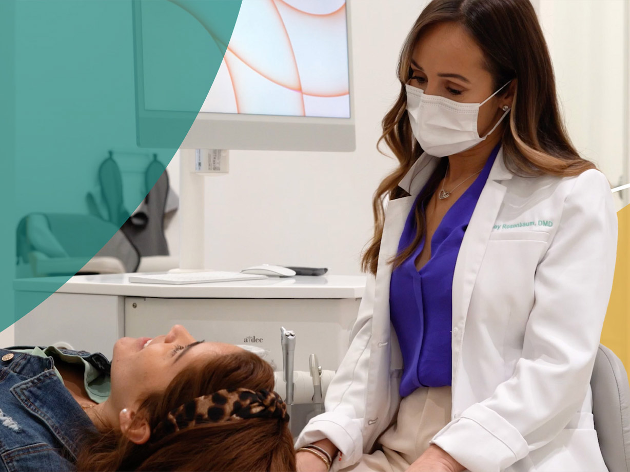 A dentist sitting in an A-dec dental stool assists a pediatric patient lying in an A-dec dental chair