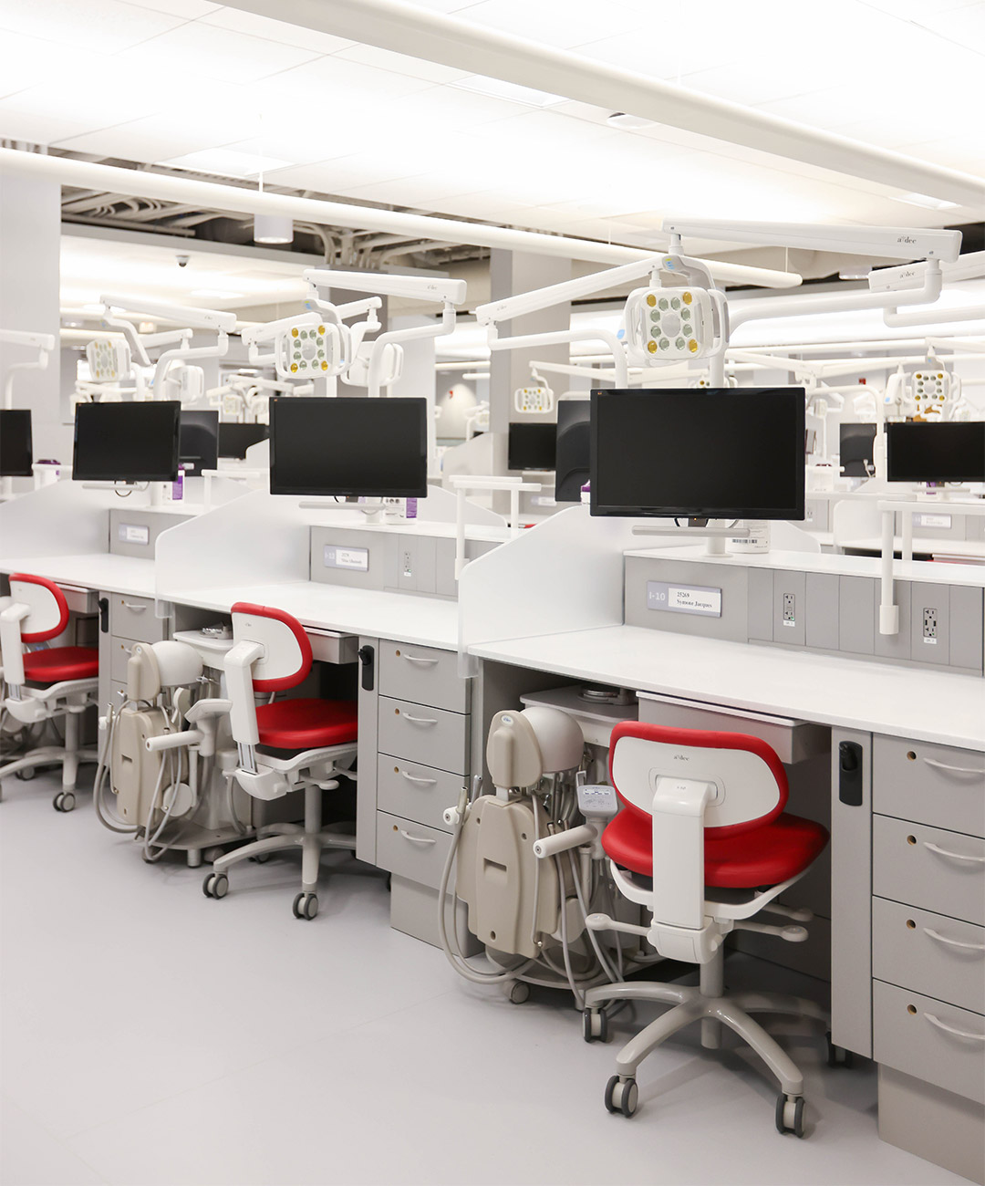 Red A-dec dental stools and A-dec Simulator Pro workstations in a classroom environment